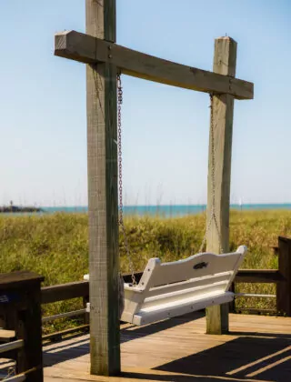 A wooden swingseat on the beach.