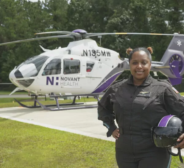 Female Flight MEDC in front of Novant Health helicopter.