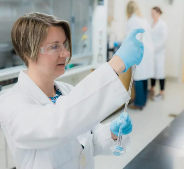 Female scientist utilizes pipette and beaker in pharmaceutical laboratory.