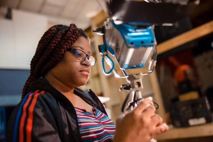 Film student setting up lighting equipment.