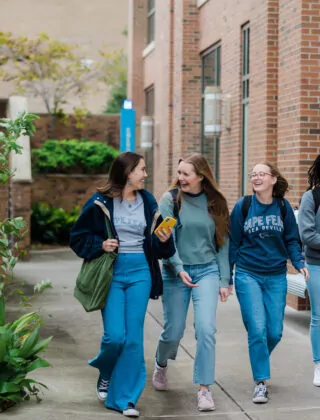 Four female students walk together outside college.
