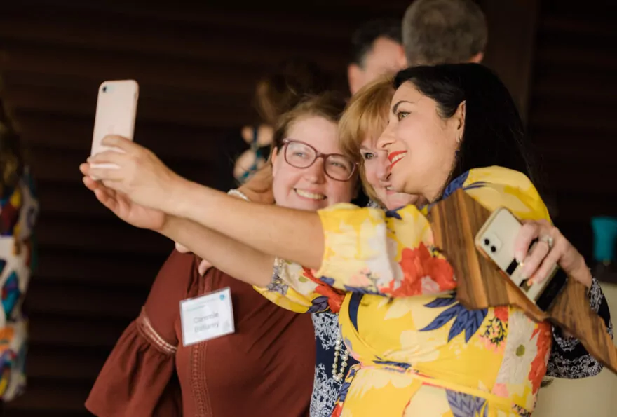 Group of three women take a selfie at a networking event.
