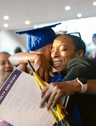 Mother hugs son at high school graduation.