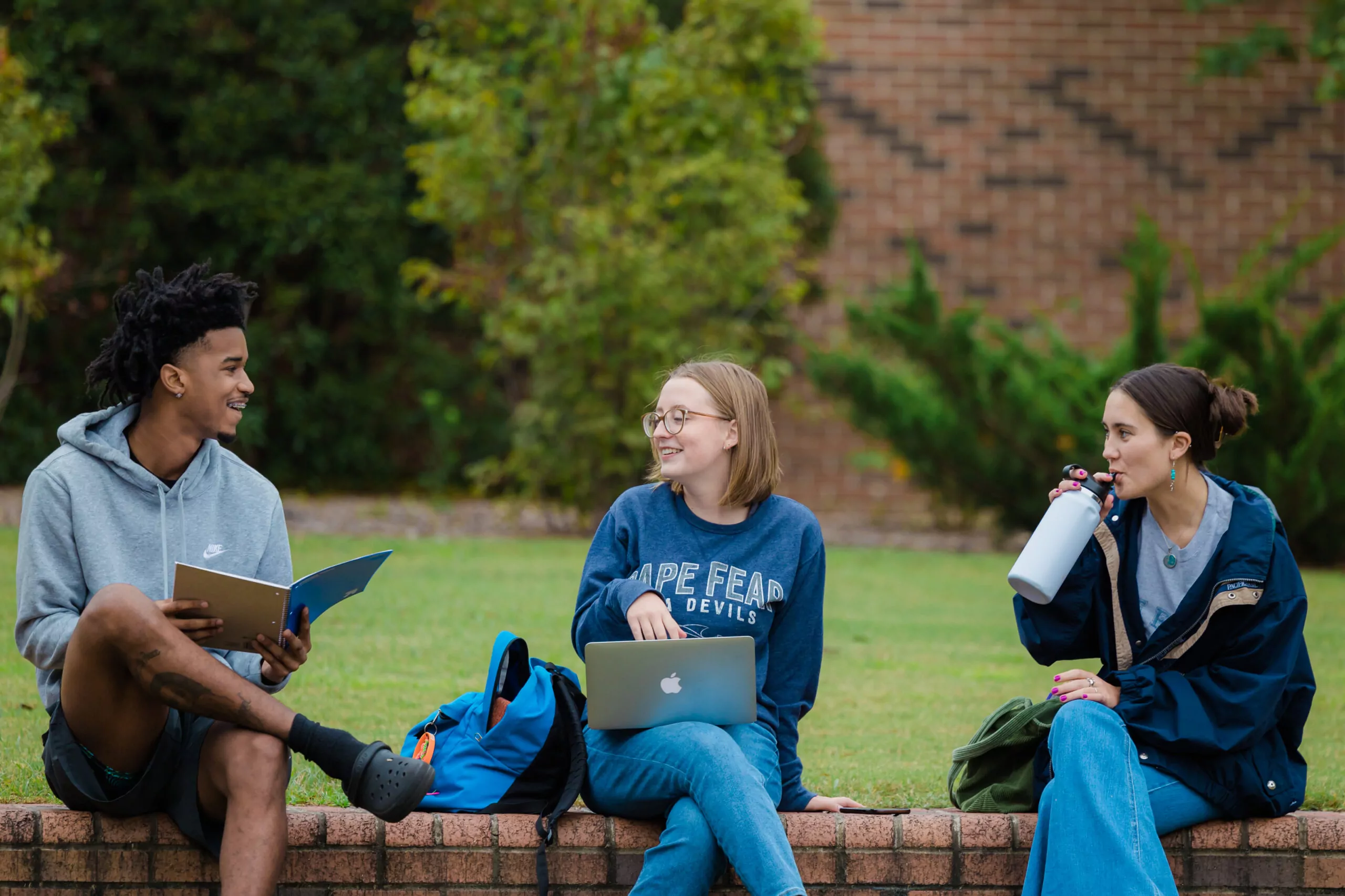 Three Cape Fear Community College students sit outside and study together.