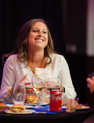 Woman smiles while speaking at networking dinner.