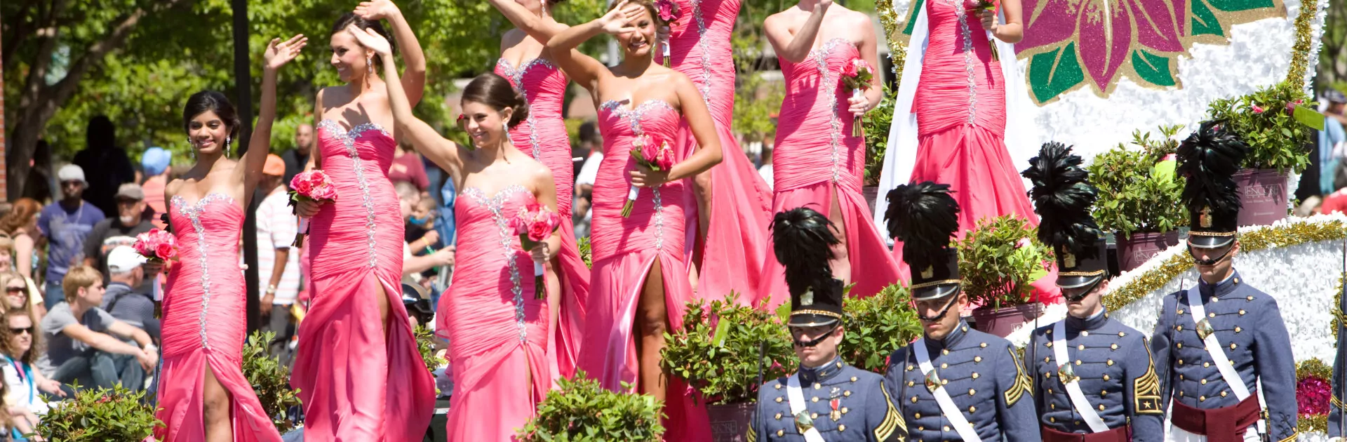 Women in matching pink dresses on a parade float for the Azalea Festival.