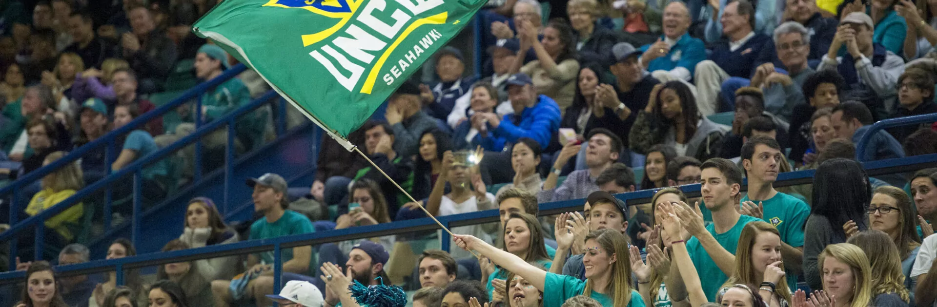 Crowd of students cheer on UNC Wilmington's basketball team.