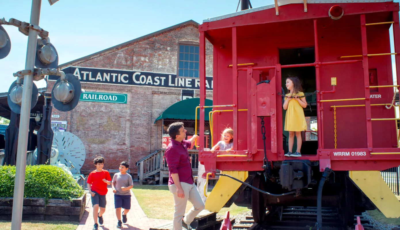Father and daughters explore reitred train car.