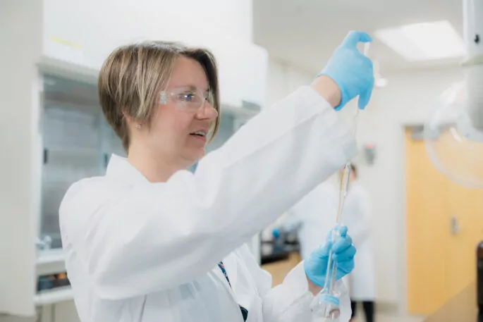 Female pharmaceutical scientist using a pipette in a lab.