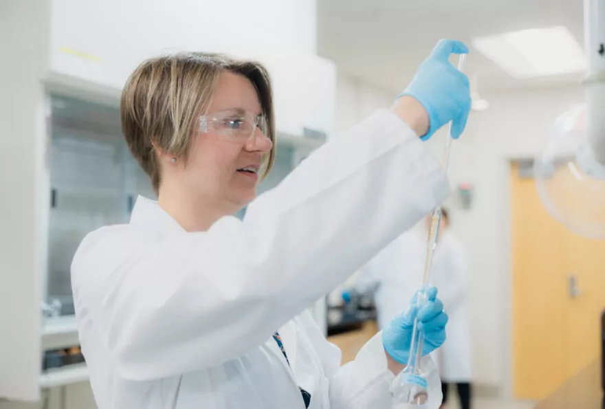 Female pharmaceutical scientist using a pipette in a lab.