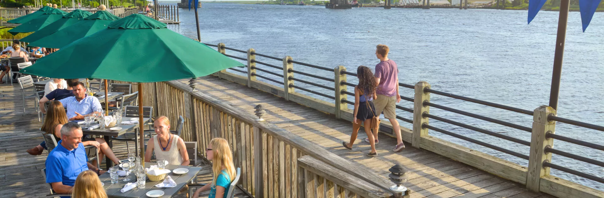 People enjoy a meal on a sunny day near the Cape Fear River.