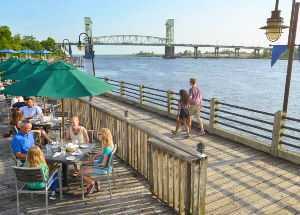 People enjoy a meal on a sunny day near the Cape Fear River.